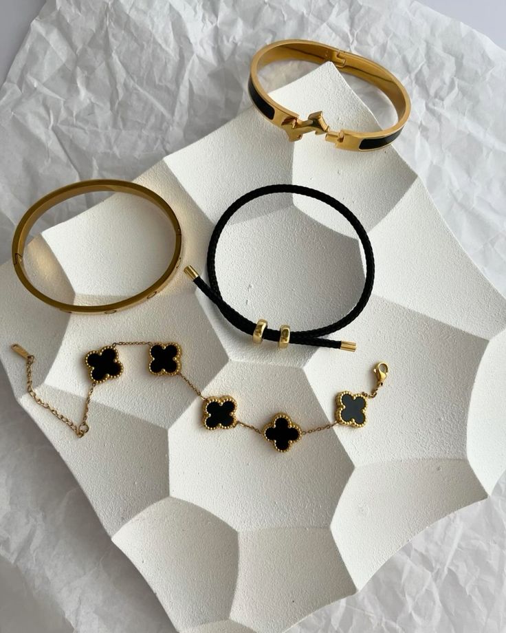 Gold bracelets and clover chain styled on white stones